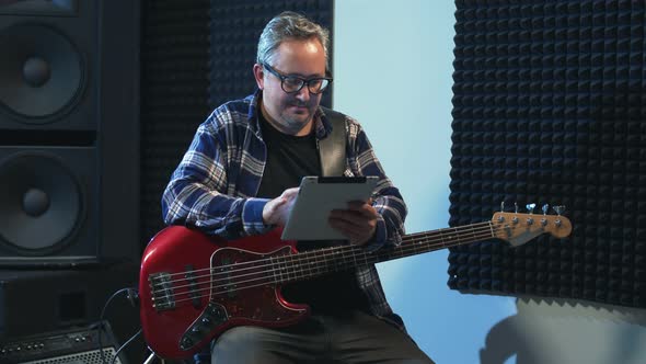 Portrait of Musician Sitting and Using Tablet in Studio