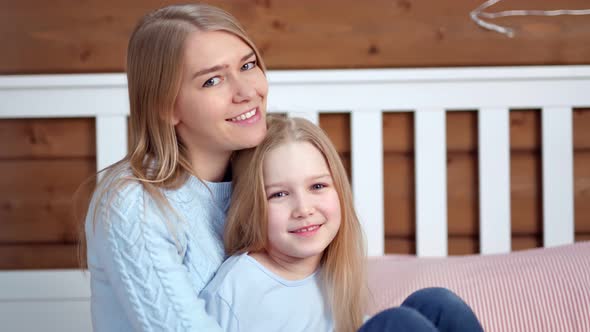 Portrait of Happiness Mother and Cute Daughter Posing and Looking at Camera at Home Interior