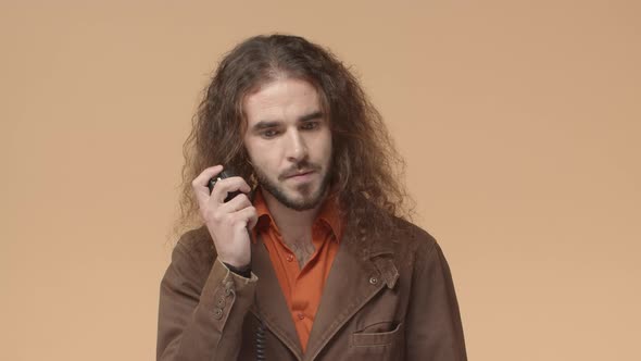 Seriouslooking Bearded Man with Long Hair Listening to Question Over Transmitter Using Radio Set to