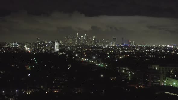AERIAL: Over Dark Hollywood Los Angeles at Night with Clouds Over Downtown and City Lights 