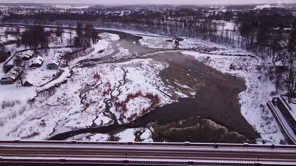 Aerial view of old red brick bridge across the Venta river in Kuldiga, Latvia in overcast winter day