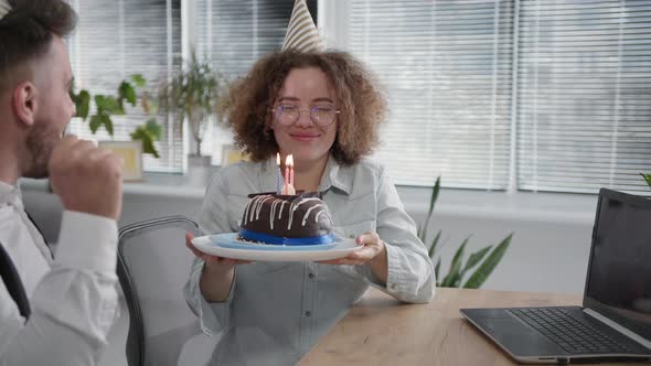 Virtual Party Joyful Man and Happy Young Woman with Party Cap Blowing Out Candles on Cake During