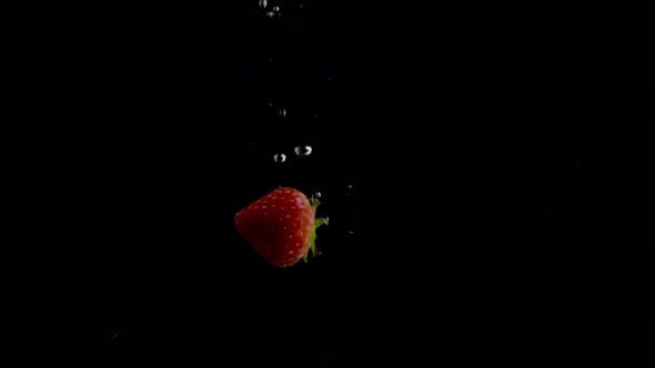 Strawberry Falling into Water Super Slowmotion, Black Background, lots of Air Bubbles, 4k240fps