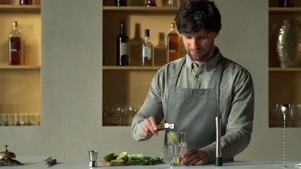 Bartender Puts Lime and Mint Leaves in a Glass to Make a Mojito Cocktail