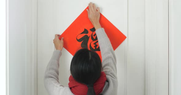 Woman sticking chinese calligraphy on the door