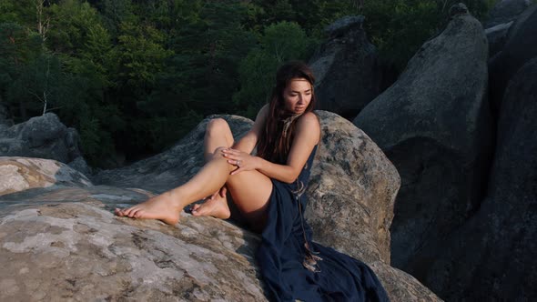 In a Blue Silk Dress a Young Woman Sat on Rocky Terrain Relaxing Outdoors in a Travel Lifestyle