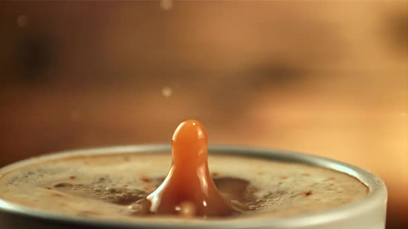 A Drop Falls Into a Cup of Coffee with Milk with Splashes