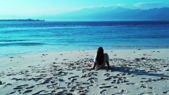 Ladies tanning on paradise lagoon beach wildlife by blue sea with white sandy background of Lombok n