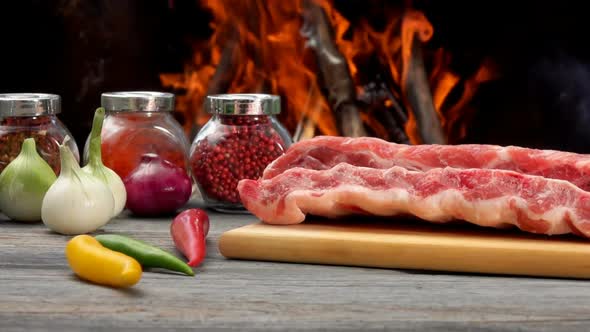 Closeup of the Raw Ribs Laying Next to Ingredients on the Background of Fire