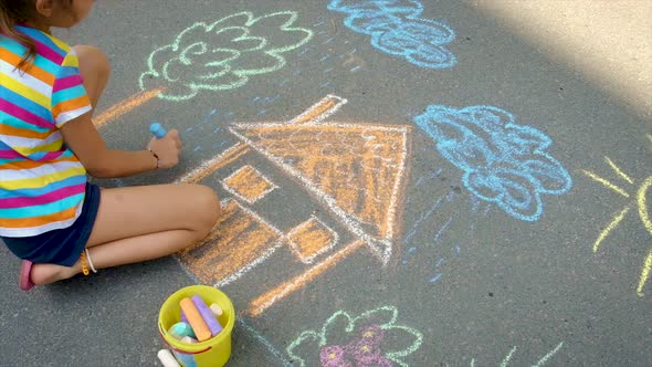 The Child Draws with Chalk on the Asphalt