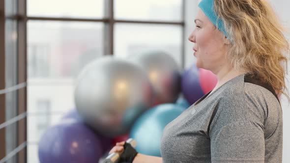 Overweight Woman Training with Dumbbells at Gym