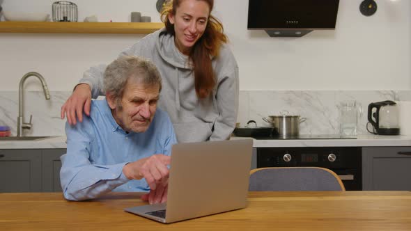 Happy Grandfather and Daughter Hugging Looking at Something on a Laptop at Home