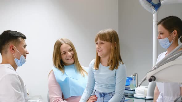 Little Cute Smiling Girl Sitting in a Dental Chair at the Clinic Together with Her Mother
