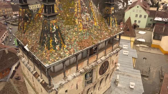 A drone shot, with panning and trucking motion combined, capturing the Sighisoara Clock Tower with a