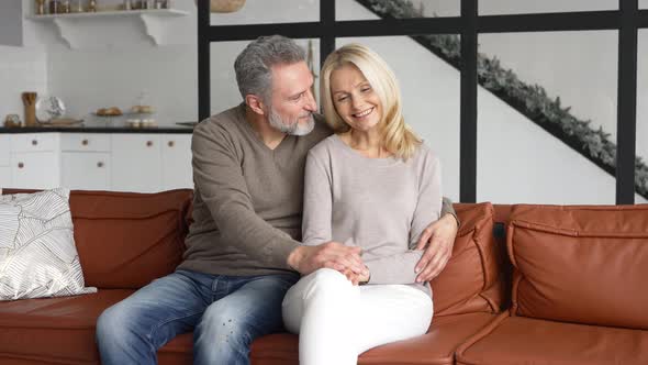 Middleaged Spouses Sits on the Sofa at Home and Look Aside at One Way