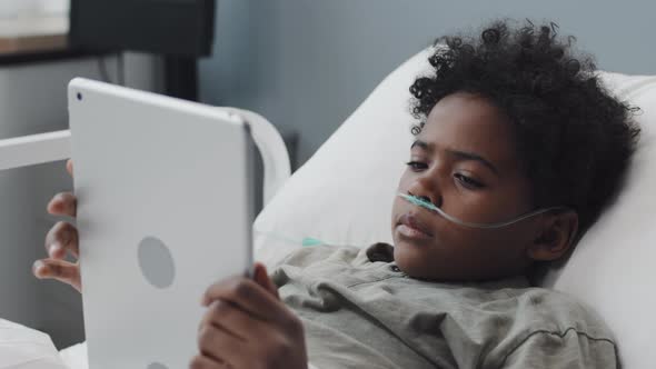 Boy Using Tablet in Hospital Bed