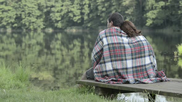 Young Romantic Couple in Nature Seated on Lake Jetty Look at Panorama in Summer Day Outdoor