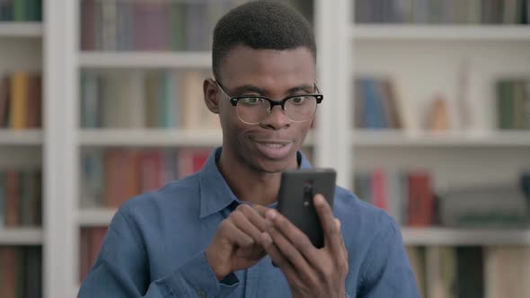 Young African Man Celebrating Win on Smartphone