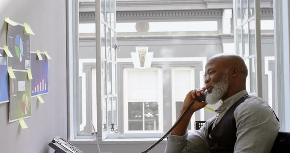 Businessman talking on landline at desk 