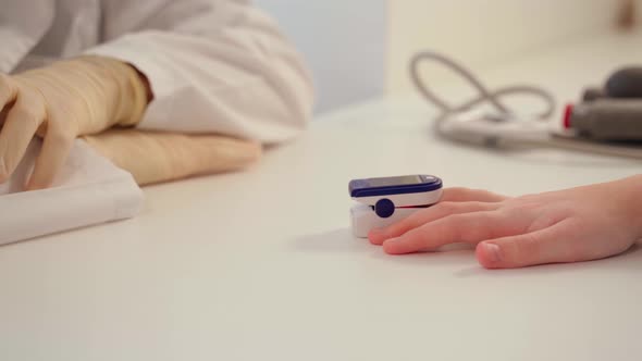 A Doctor in Latex Gloves Using a Pulse Oximeter Measures the Level of Oxygen in the Patient's Blood