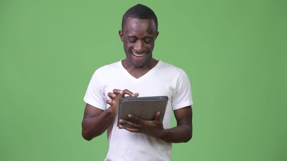 Young Happy African Man Using Digital Tablet Against Green Background