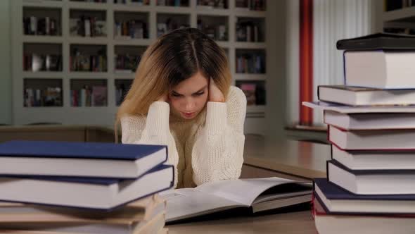 A Tired Young Student Girl Reads a Difficult Book in the Library