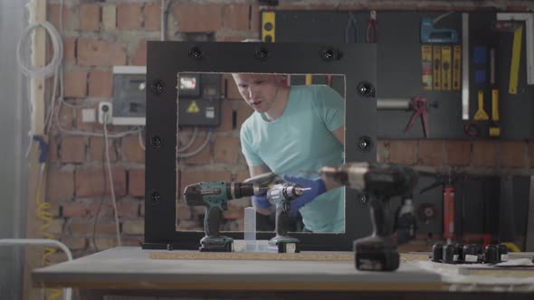 Female Worker on the Furniture Factory Testing the Drill Screwdriver. Profession of the Carpenter