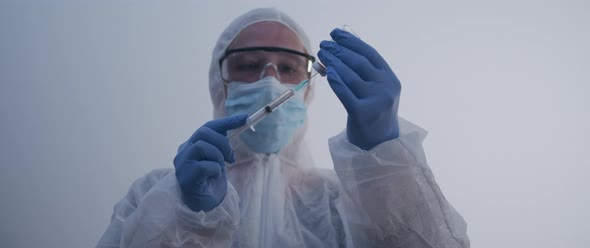 Woman extracting fluid with syringe and pulls the needle out slow motion