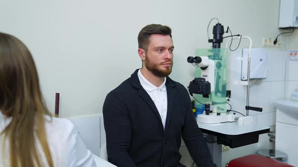 Patient during vision test. Young male patient checking up vision, closing his eye