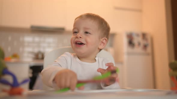 Little Cute Baby Toddler Boy Blonde Sitting on Baby Chair Learning Draw with Colour Pencils