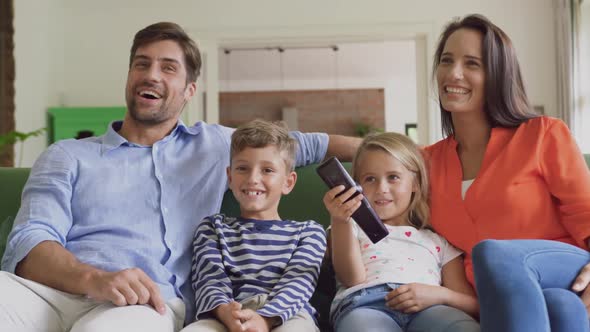 Family watching television together in living room at home 4k