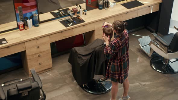 Barbershop: a woman barber cuts a client's man's hair