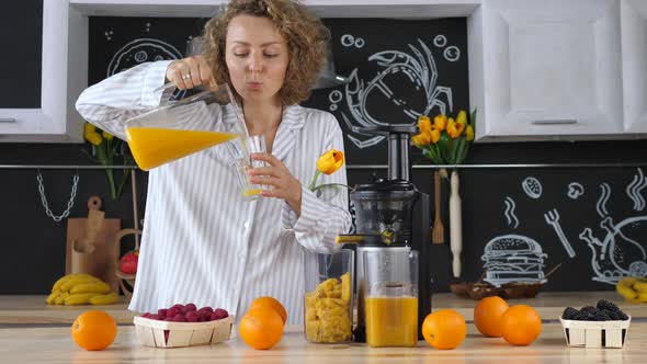 Young Woman Drinking Fresh Orange Juice In Kitchen