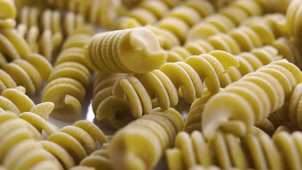 Fusilli Italian uncooked pasta. Falling green pea vegetable spiral macaroni in slow motion. Macro