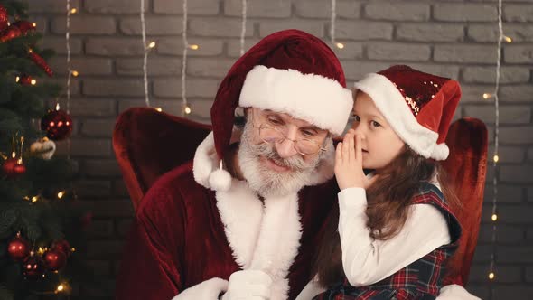 Girl in Red Hat Whispering a Wish To Santa
