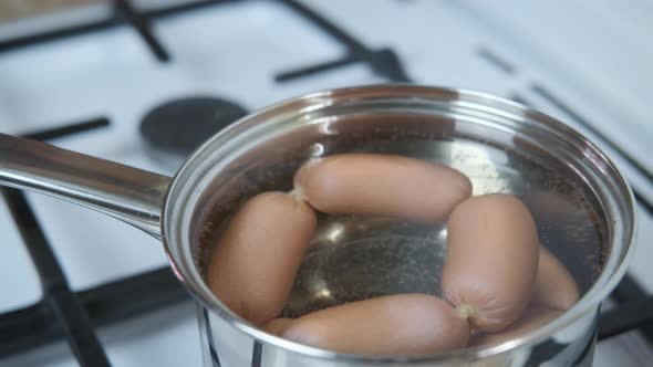 Sausages are cooked in a pan on the stove.