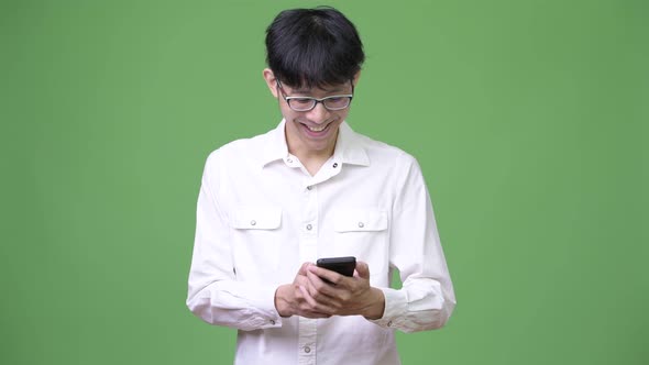Happy Young Asian Businessman Smiling While Using Phone