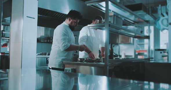 Two chefs prepare spices in industrial kitchen