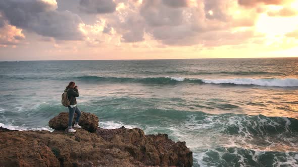 A Photographer Taking Pictures of Big Waves Crashing Against Rocks