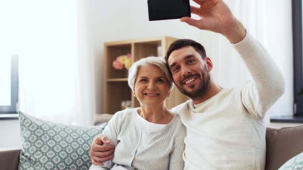 Senior Mother with Adult Son Taking Selfie at Home