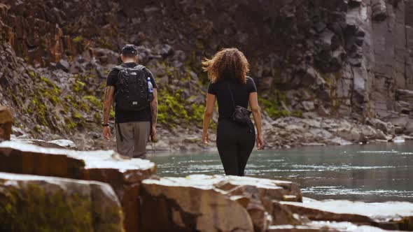 Male and Female Travelers Walking Towards the Studlagil Canyon's Riverside