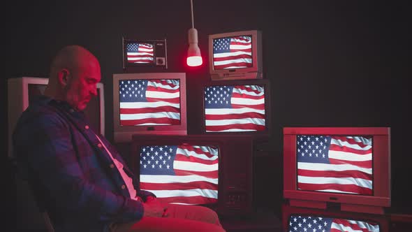 A Man Sits in Front of a Wall of Televisions