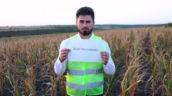 Portrait of a Young Depressed Farmer Holding a Placard in His Hand with the Message Save the Farmers