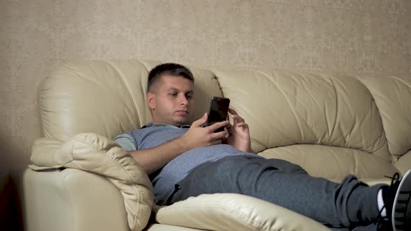 Man Using a Mobile Phone at Home on the Sofa.