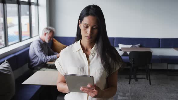 Mixed race businesswoman standing using digital tablet in modern office