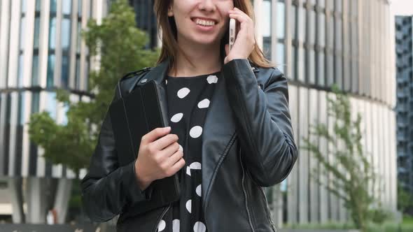 Young Business Woman Talking on the Smartphone Near Business Center with Tablet in the Hand