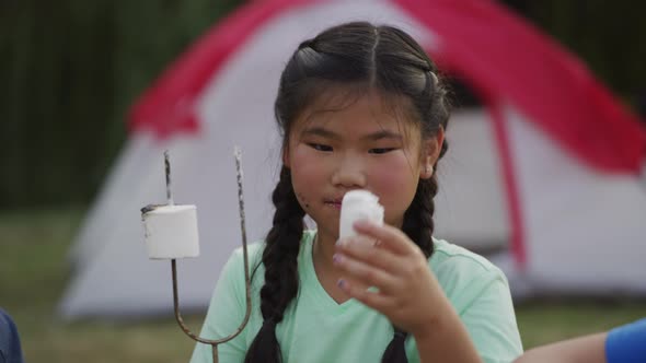 Young girl at summer camp eating a marshmallow