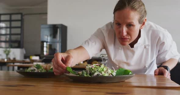 Caucasian female chef preparing a dish and smiling in a kitchen