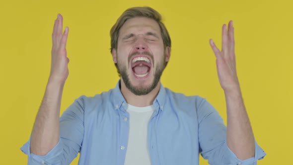 Young Man Shouting and Screaming on Yellow Background
