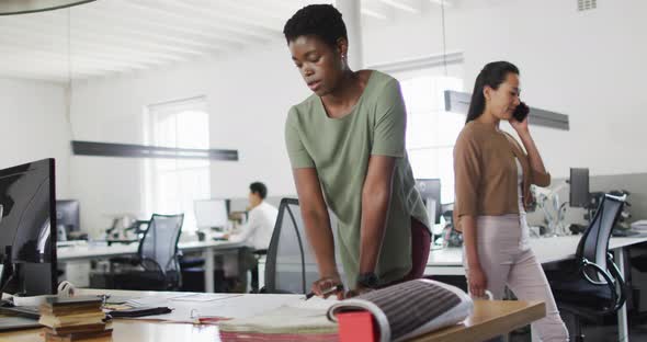 Focused african american businesswoman standing at desk and making notes in office